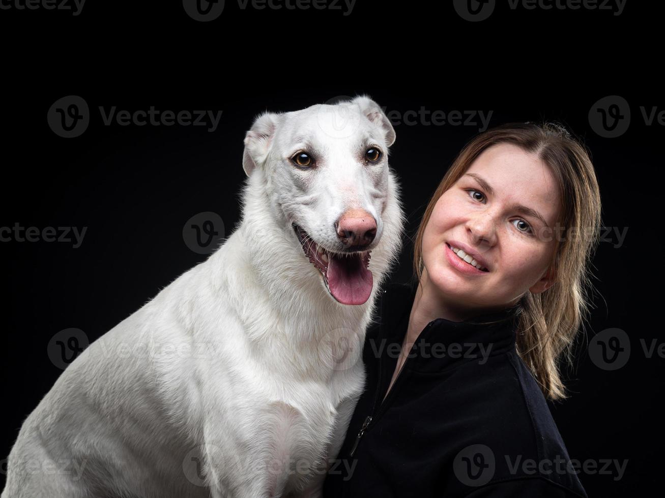 jeune jolie femme pose avec son animal de compagnie blanc, mis en valeur sur fond noir. photo