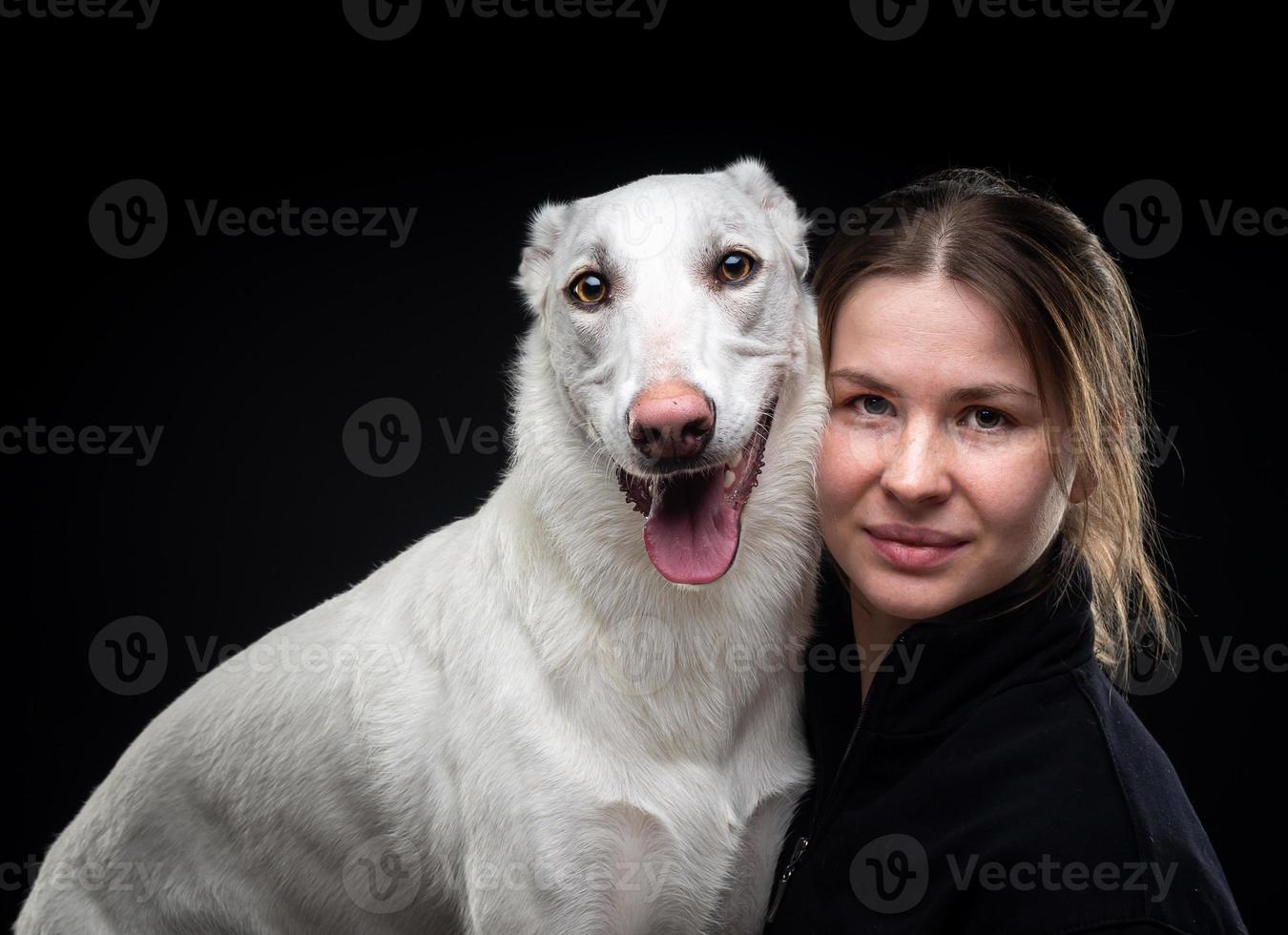 jeune jolie femme pose avec son animal de compagnie blanc, mis en valeur sur fond noir. photo