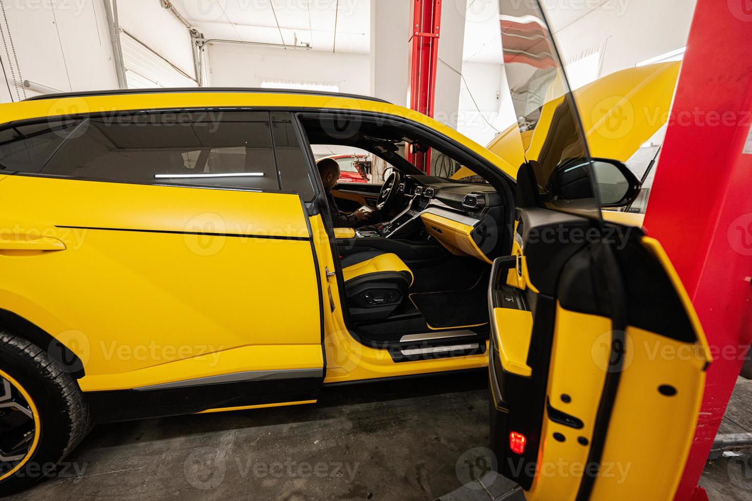 mécanicien à l'aide d'une tablette numérique, assis dans une voiture de sport jaune suv. photo