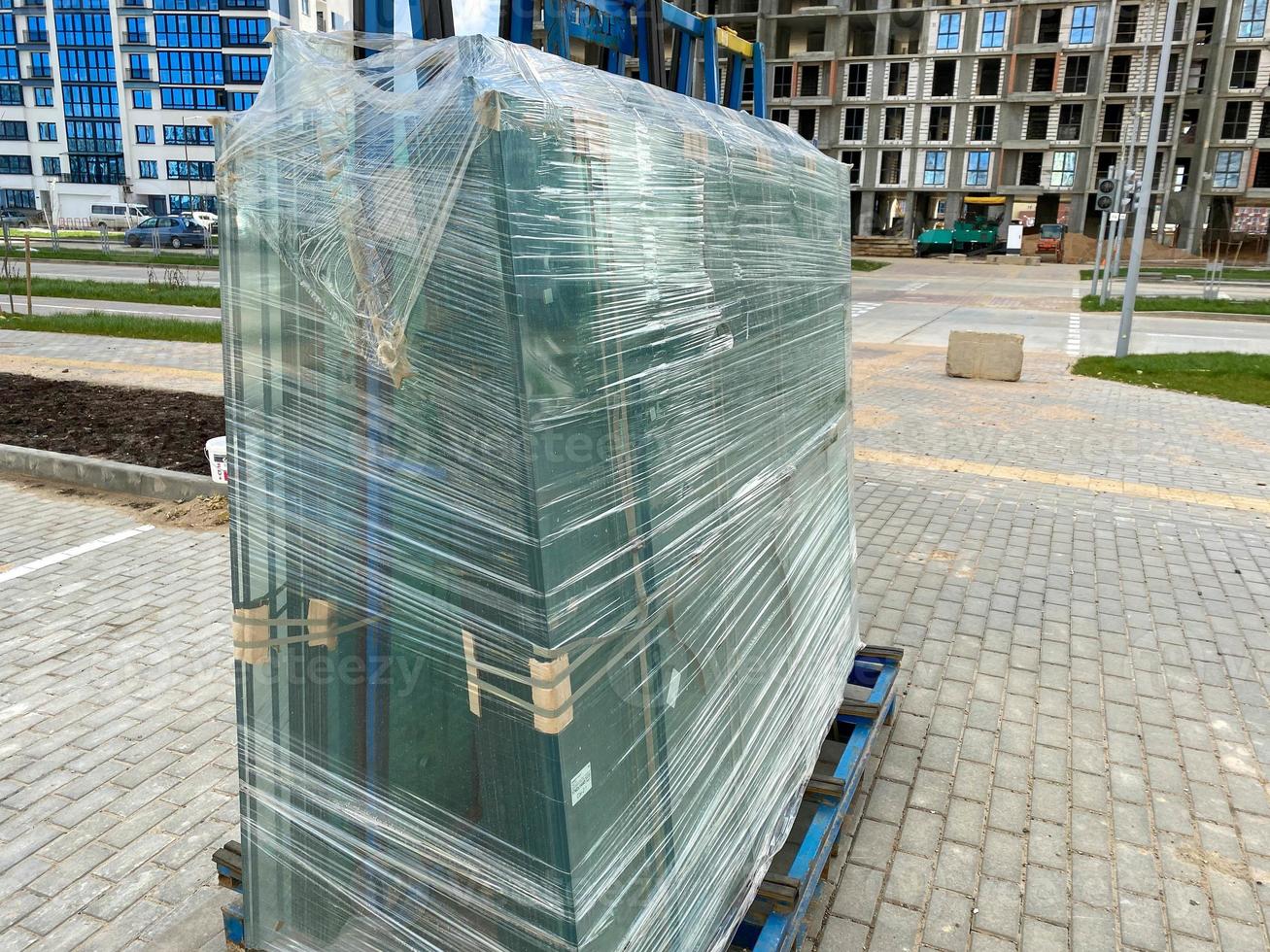 un grand paquet de verre pour fenêtres à double vitrage enveloppé de film étirable sur le chantier lors de la construction de maisons photo