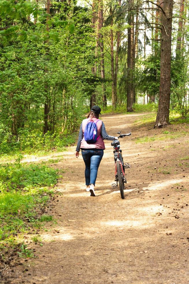 une femme à vélo, une fille européenne s'est arrêtée à vélo pour se détendre dans la forêt photo