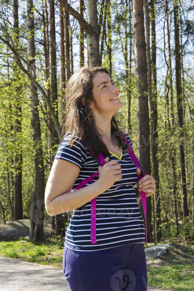 portrait d'une jolie jeune brune en t-shirt avec sac à dos, femme séduisante caucasienne marchant dans le parc en été, belle jeune femme, marchant photo