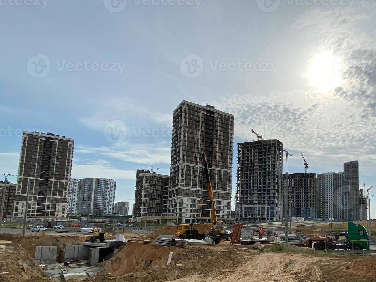 de grands bâtiments et maisons modernes et magnifiques sont des gratte-ciel en béton construits industriellement à l'aide d'une technologie de châssis monolithique à l'aide d'équipements de construction et de grues photo