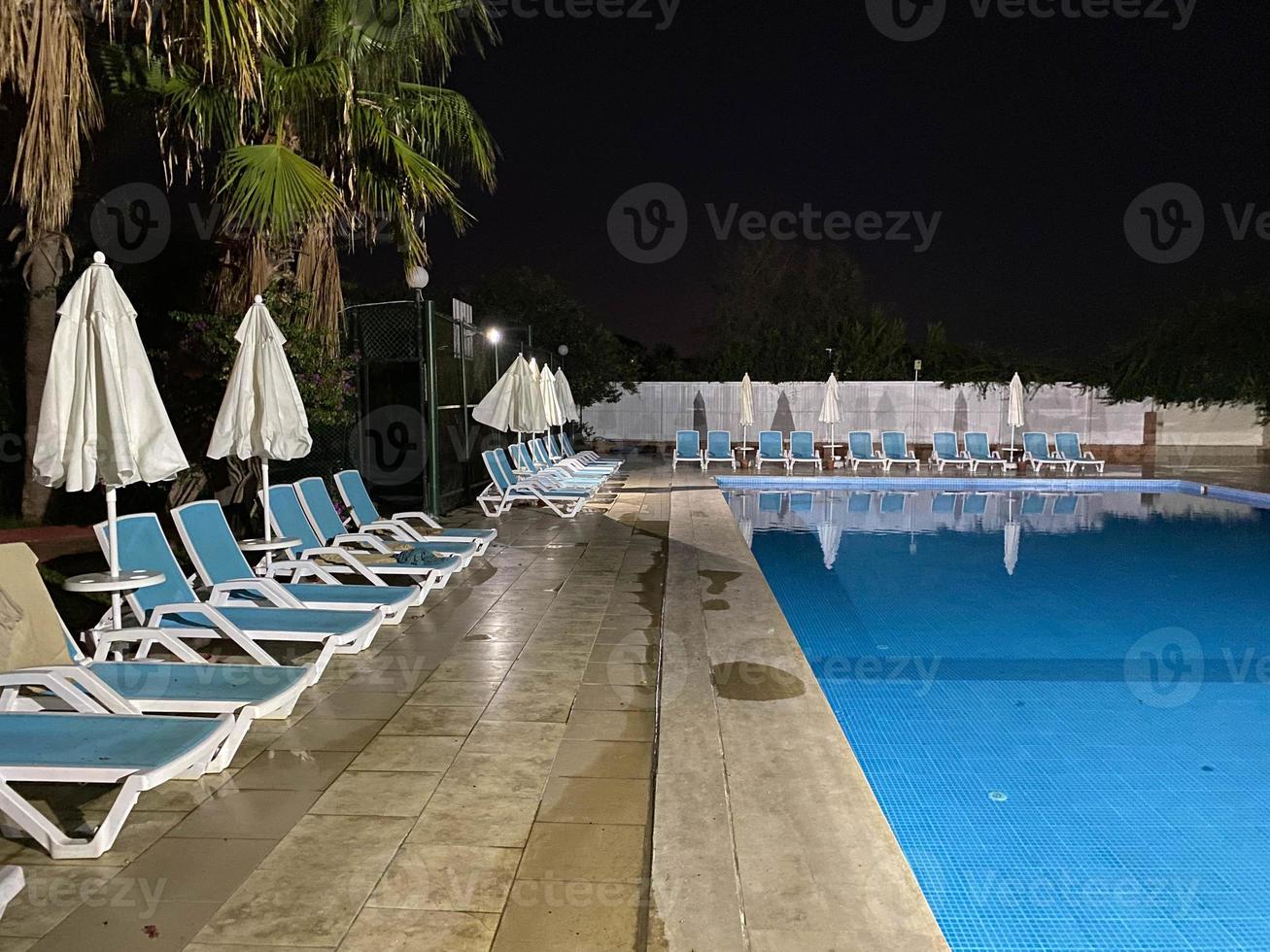 belle piscine de nuit avec parasols et chaises longues et palmiers dans un hôtel en vacances dans une station balnéaire du sud de l'est tropical chaud touristique photo