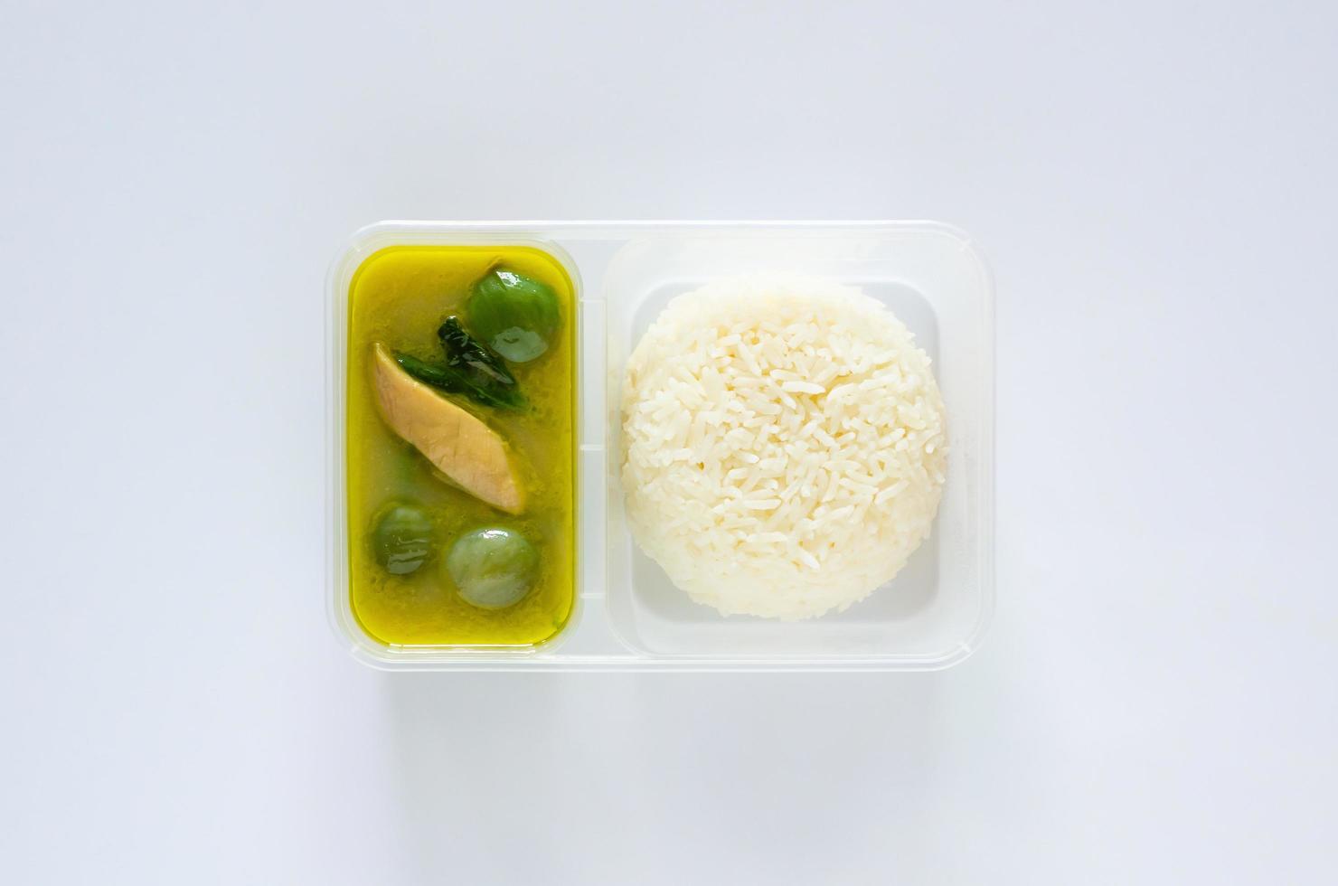 vue de dessus du curry vert thaïlandais à emporter avec du riz au jasmin dans une boîte en plastique sur fond blanc. photo