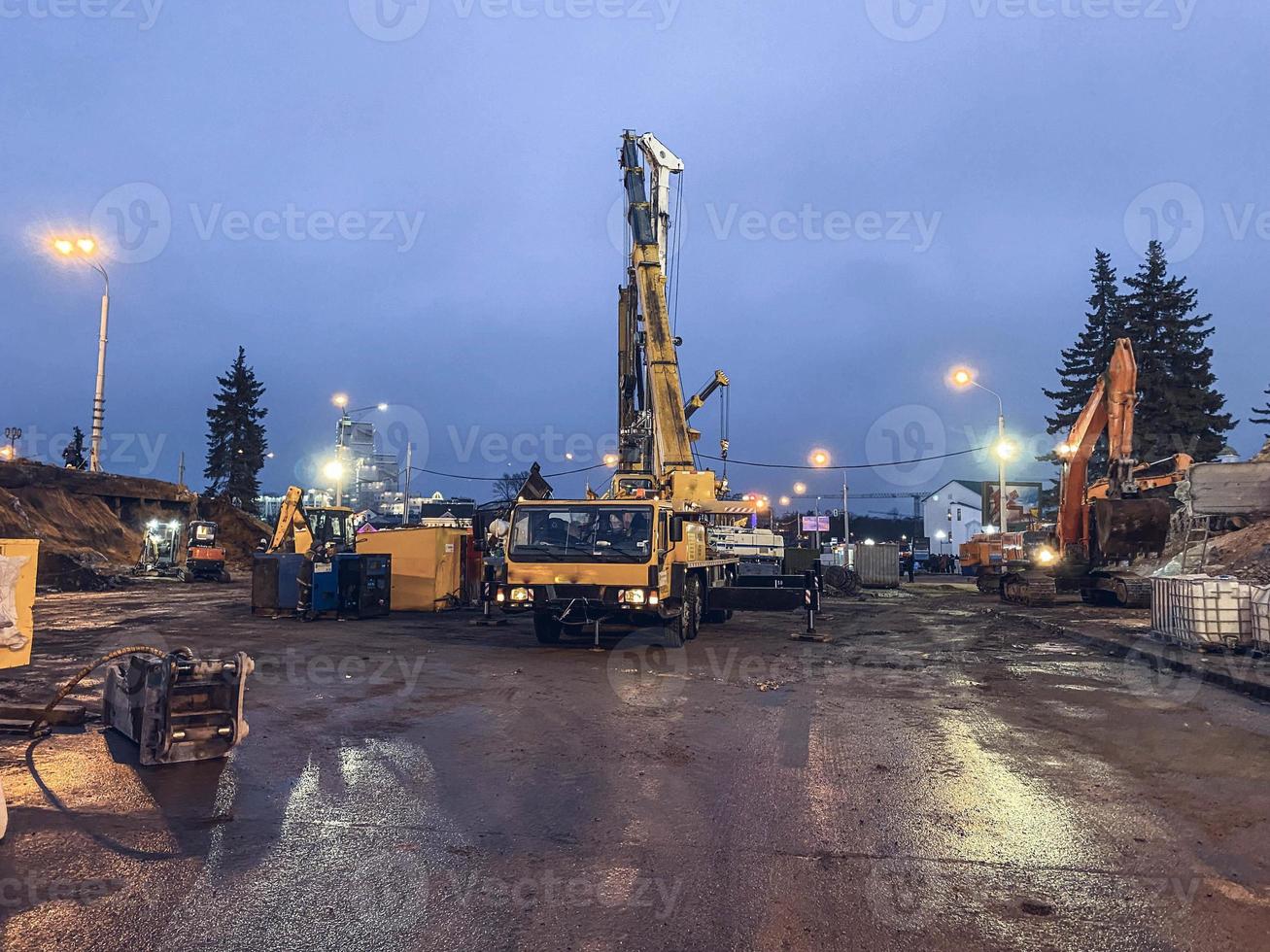 construction d'un pont en centre-ville. l'équipement de construction est utilisé pour construire un immense viaduc à partir de blocs de béton. les gens travaillent sur une chaussée mouillée photo