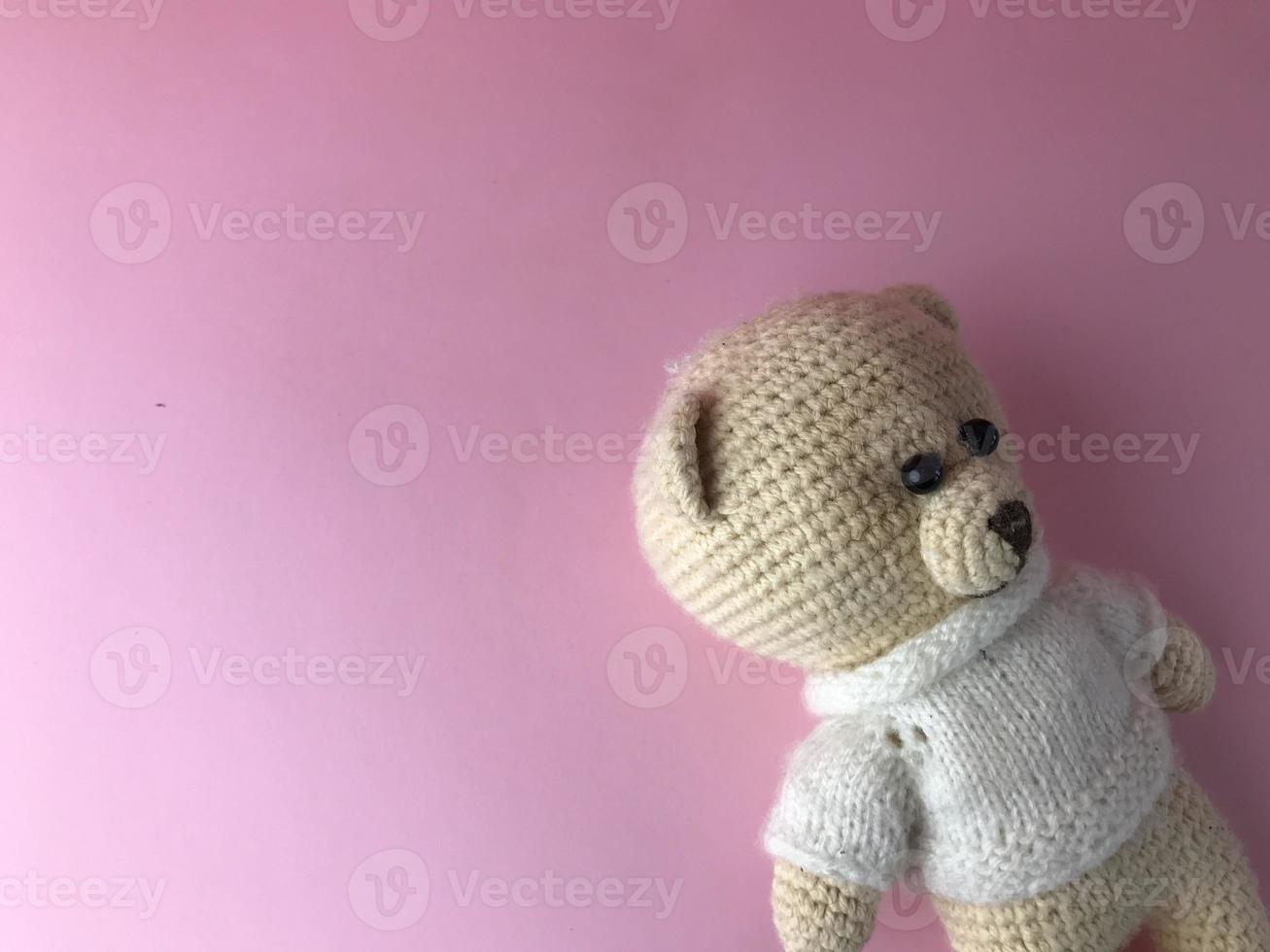 jouet intérieur - un ours tricoté doux sur fond rose dans le coin de l'arrière-plan. ours en matières naturelles, crocheté de fils. cadeau mignon photo