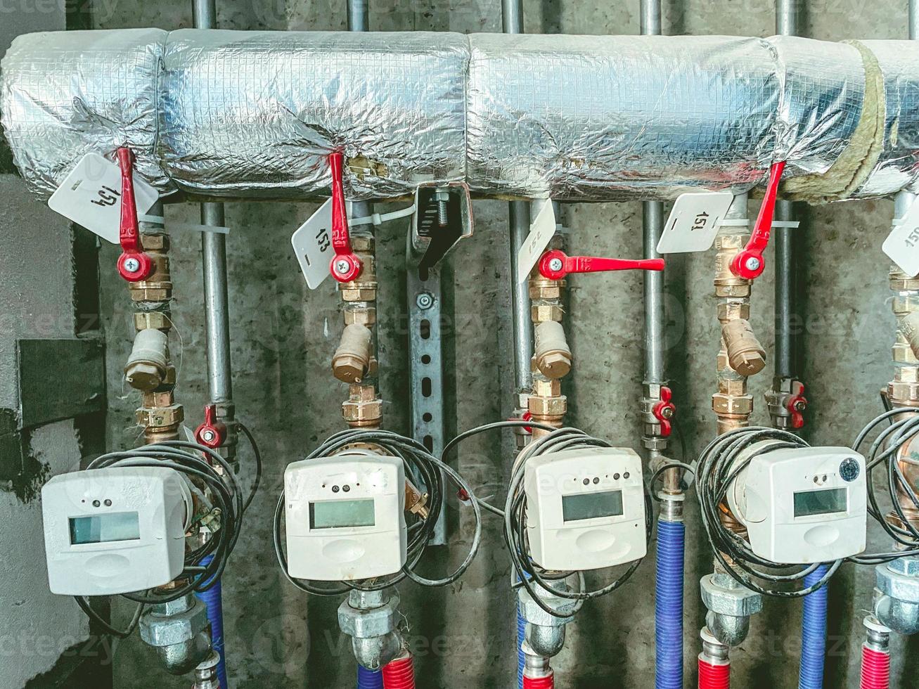 compteurs dans un immeuble résidentiel pour mesurer l'énergie thermique. compteurs avec robinets rouges sur un tuyau métallique en papier d'aluminium. fournir des ressources aux résidents de la maison photo