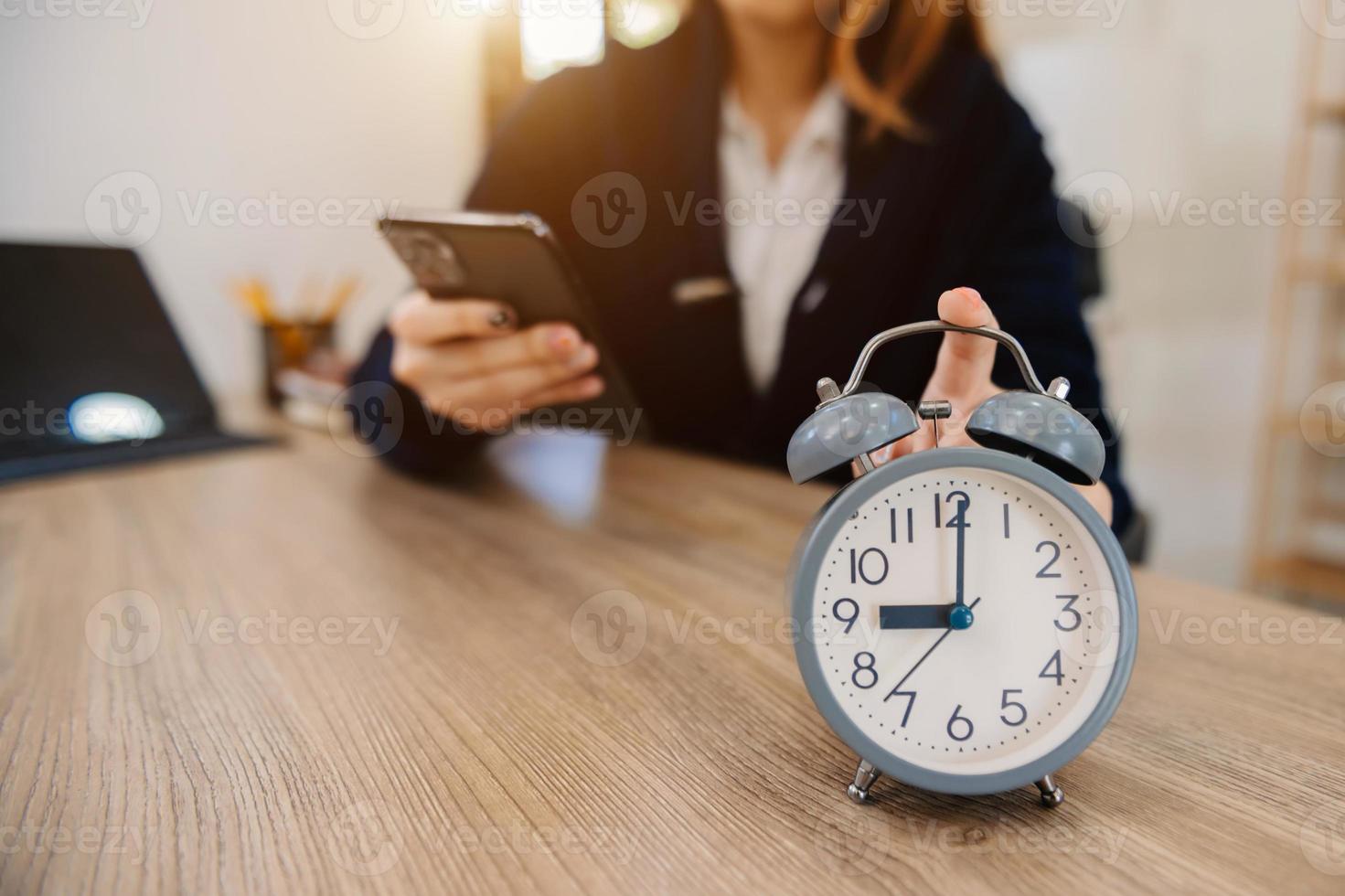 réveil sur le bureau. entreprise travaillant dans un immeuble de bureaux moderne ou à la maison la nuit à l'aide d'un ordinateur portable. photo