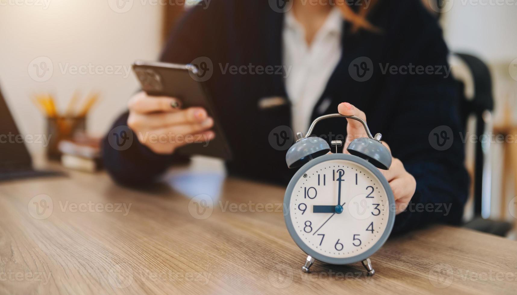 réveil sur le bureau. entreprise travaillant dans un immeuble de bureaux moderne ou à la maison la nuit à l'aide d'un ordinateur portable. photo