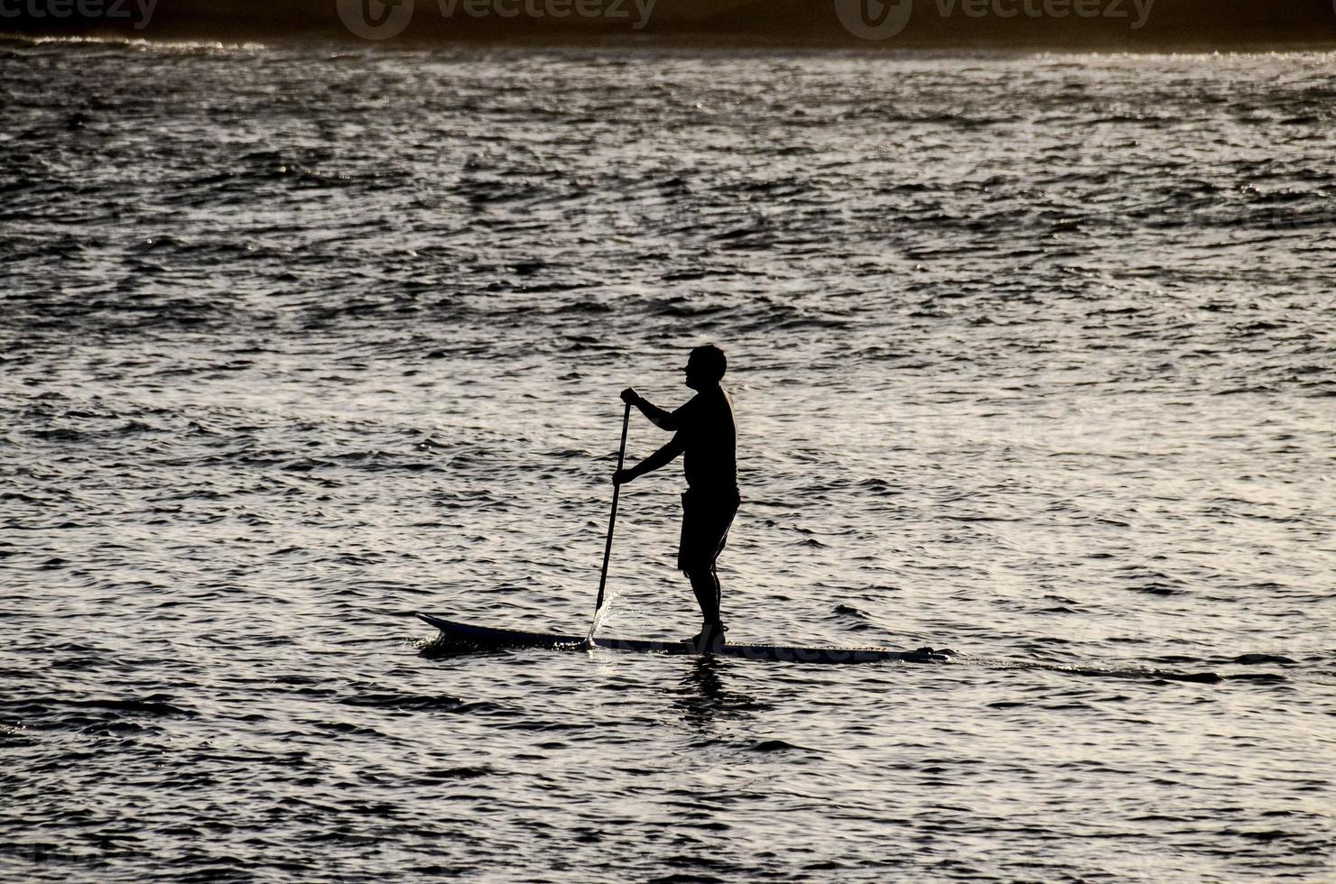 silhouette d'un homme en planche à pagaie photo