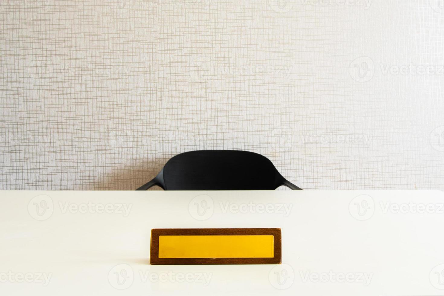 espace de nom vide sur une plaque de bureau jaune sur une table blanche avec une chaise. maquette réaliste de vecteur de table blanche de bureau en bois avec plaque de bureau vierge, identification ou plaque signalétique isolée photo