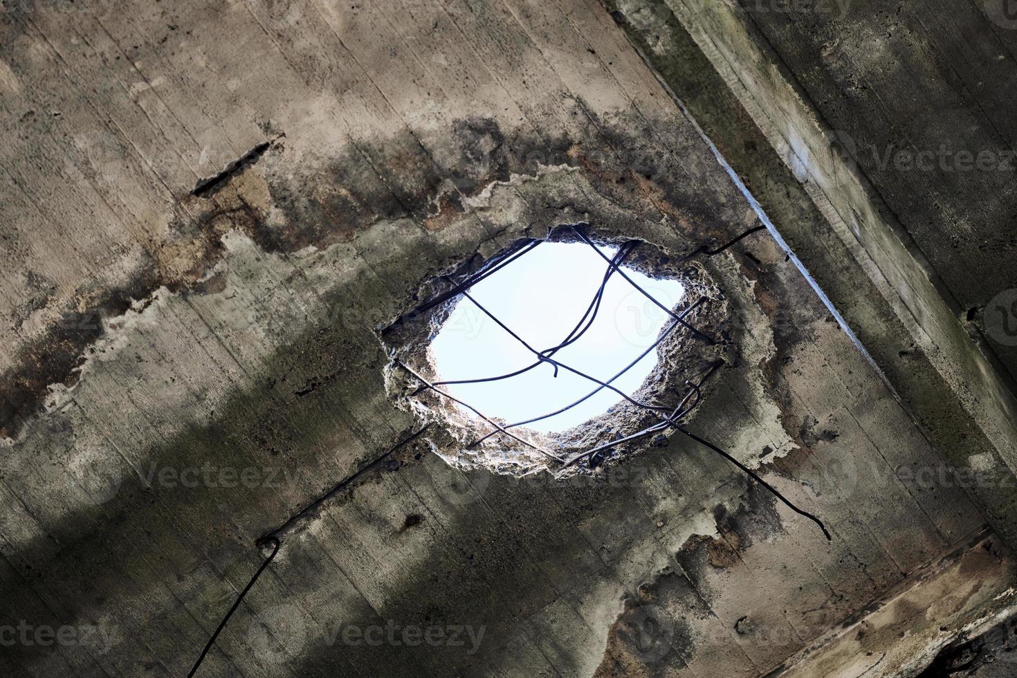 Toit endommagé abandonné avec trou dans le plafond donnant sur ciel nuageux, gros plan photo