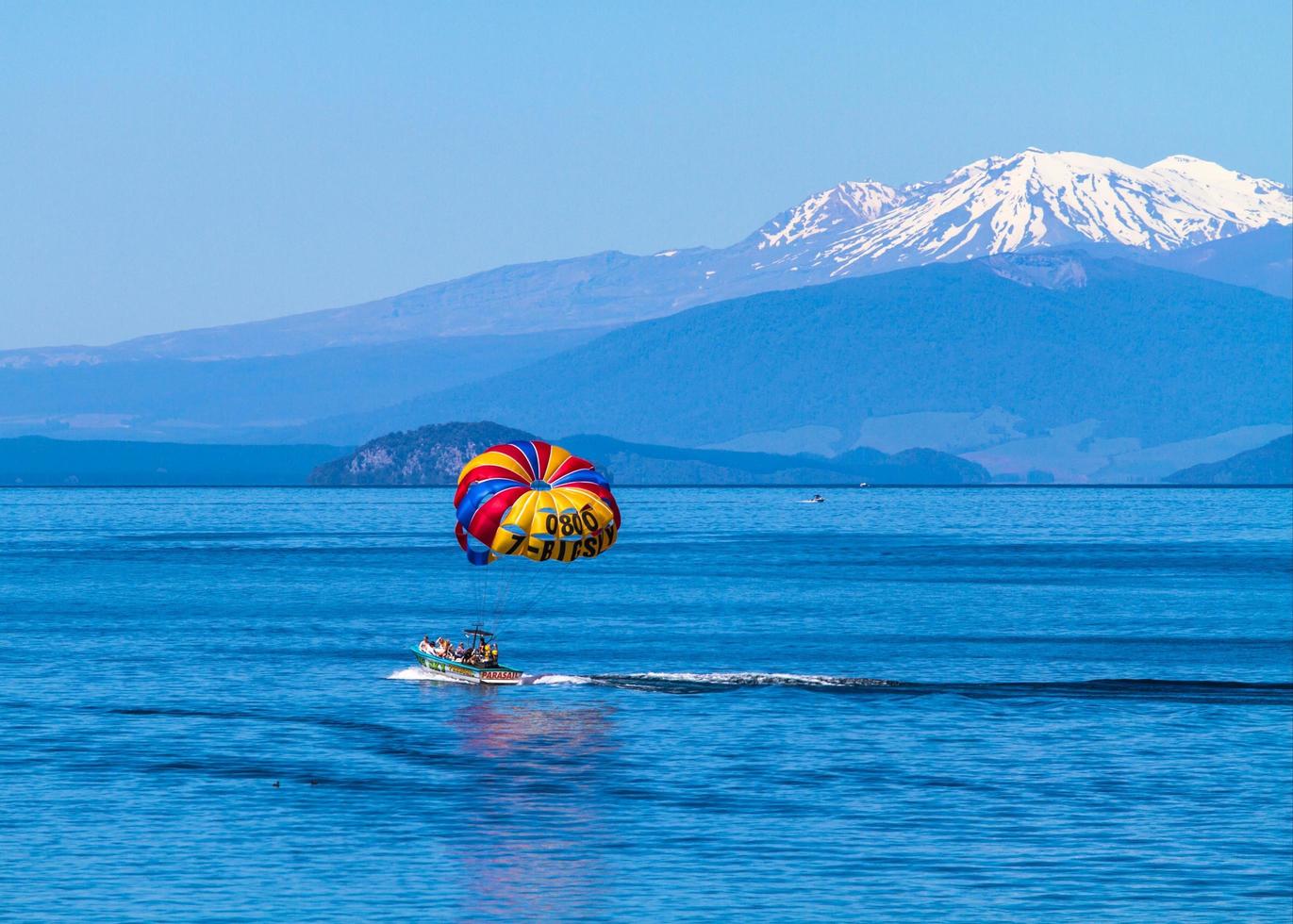 Lake Taupo, Nouvelle-Zélande, 2020 - Un groupe de parachute ascensionnel à cheval sur un bateau près des montagnes photo