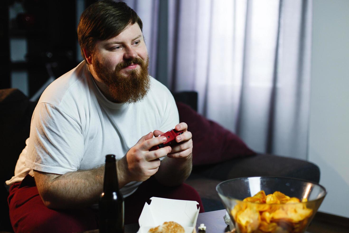 Heureux gros homme en chemise sale joue à des jeux vidéo photo