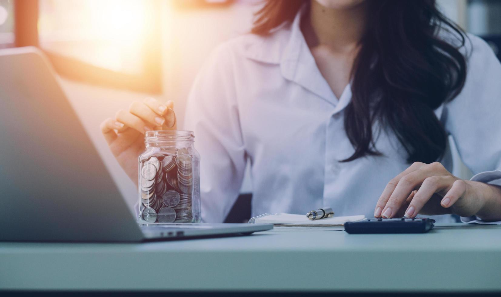 les femmes d'affaires mettent de l'argent de la pile de pièces et de nombreux billets de banque au bureau, économisent de l'argent pour l'avenir et la retraite. photo