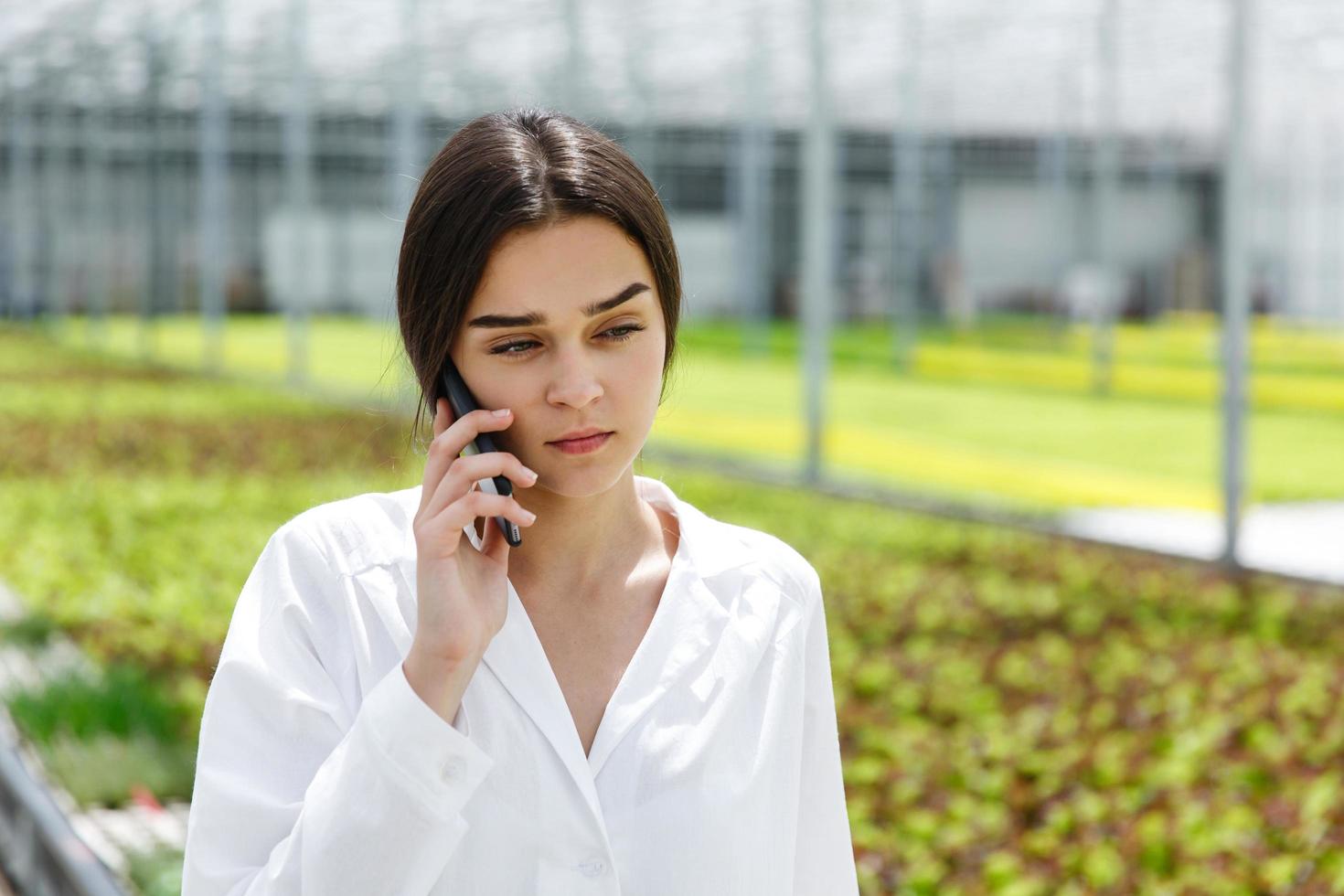 un chercheur parle au téléphone en se promenant dans une serre photo