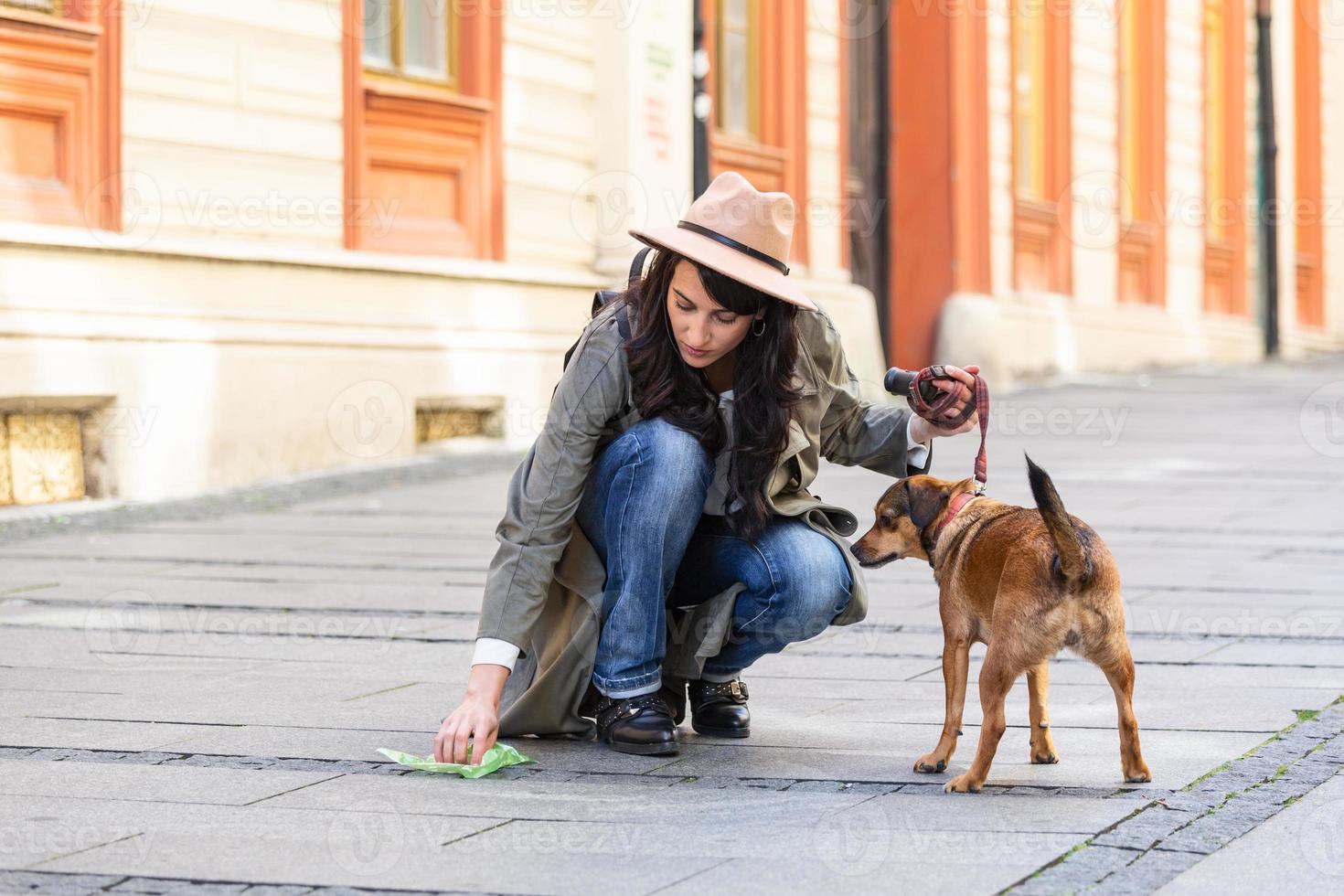 jeune femme nettoyant les excréments de chiens dans la rue, le propriétaire de l'animal ramasse la merde du chien nettoyant le désordre. photo