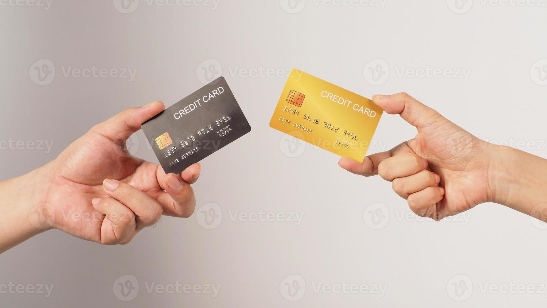 deux mains tiennent une carte de crédit noire et or sur fond blanc. photo