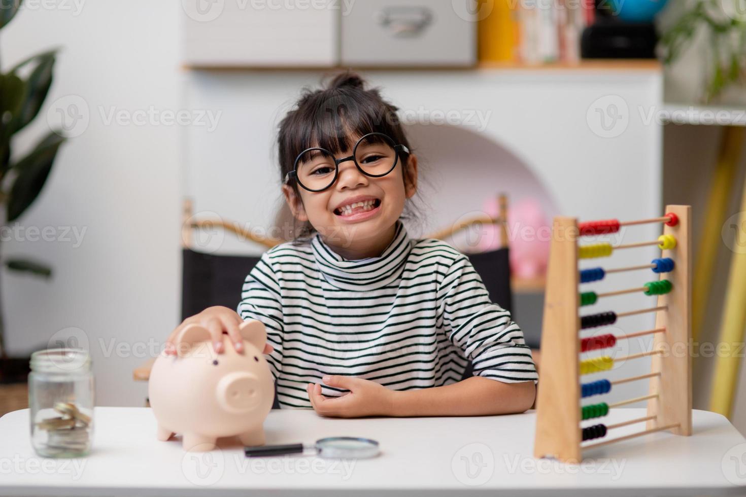 petite fille asiatique économisant de l'argent dans une tirelire, apprenant à économiser, enfant économisant de l'argent pour l'éducation future. concept d'argent, de finances, d'assurance et de personnes photo