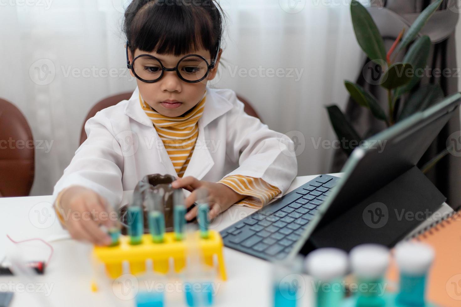 petite fille asiatique mesurant la température de l'eau chaude et froide pour un cours en ligne expérimental scientifique facile photo