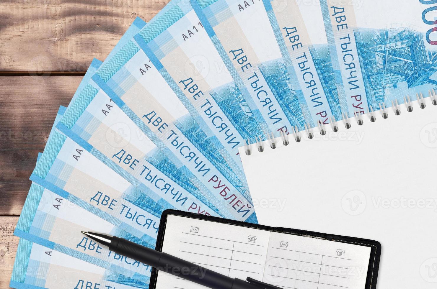 Éventail de billets de 2000 roubles russes et bloc-notes avec carnet de contacts et stylo noir. concept de planification financière et de stratégie d'entreprise photo