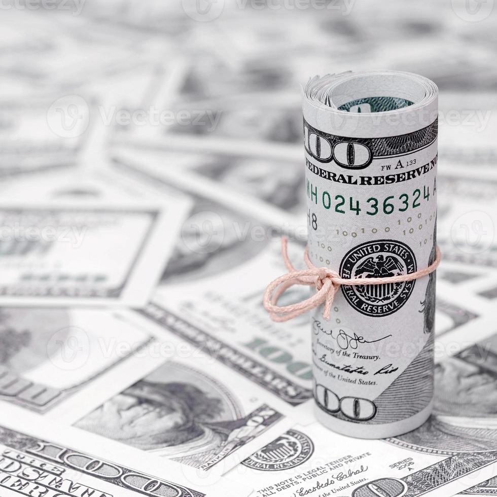 dollars américains enroulés et resserrés avec une bande se trouve sur beaucoup de billets américains avec un arrière-plan flou photo
