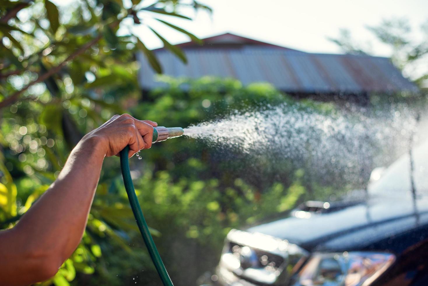 main tenant le tuyau de lavage de voiture photo