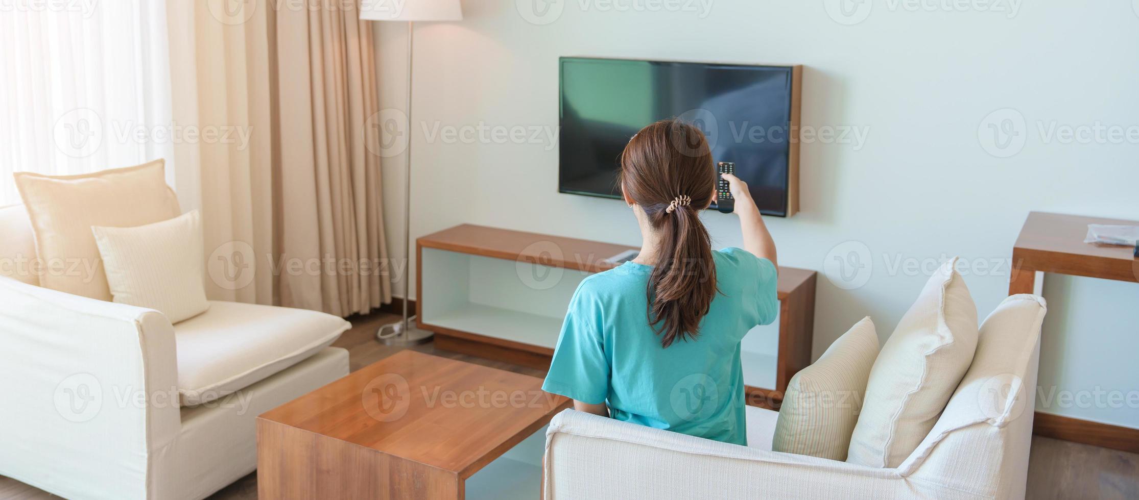 femme se reposant sur le canapé, fille utilisant la télécommande et choisissant une émission de télévision et une série de films pendant le repos sur le canapé le matin. concept de vie en appartement photo