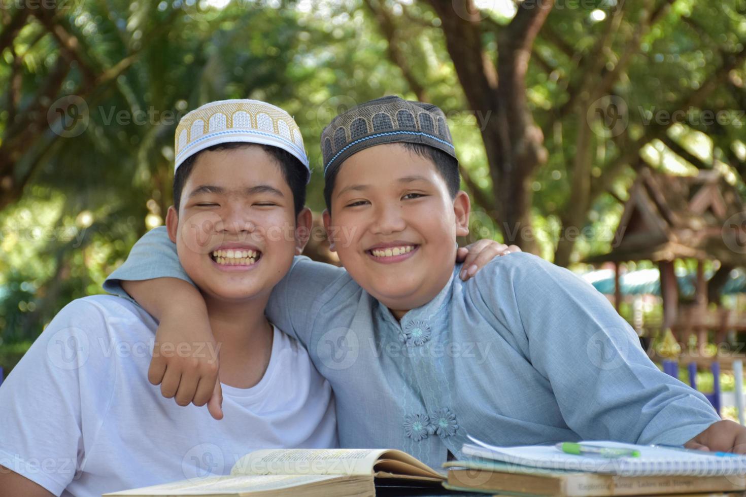 les garçons musulmans asiatiques s'assoient ensemble dans le parc de l'école pour lire et apprendre leur activité quotidienne et faire leurs devoirs pendant leurs temps libres avant de rentrer à la maison, mise au point douce et sélective. photo