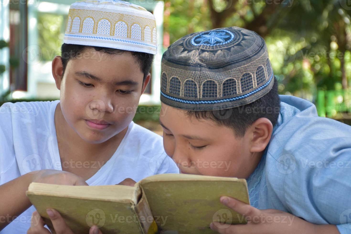 les garçons musulmans asiatiques s'assoient ensemble dans le parc de l'école pour lire et apprendre leur activité quotidienne et faire leurs devoirs pendant leurs temps libres avant de rentrer à la maison, mise au point douce et sélective. photo