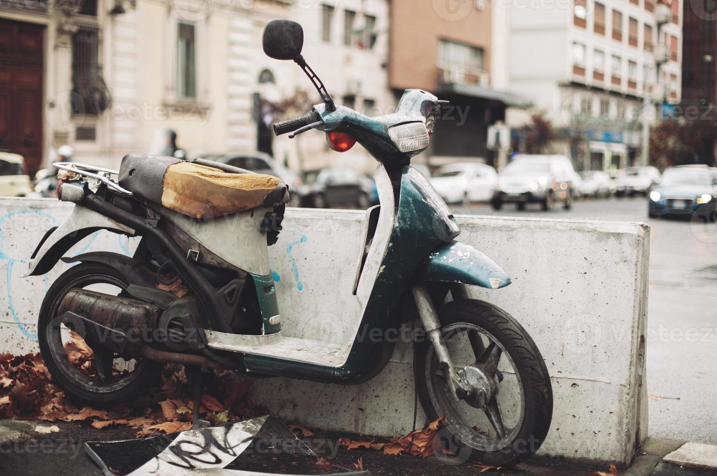 une vieille moto, rouillée et cassée, abandonnée au milieu de la ville. photo