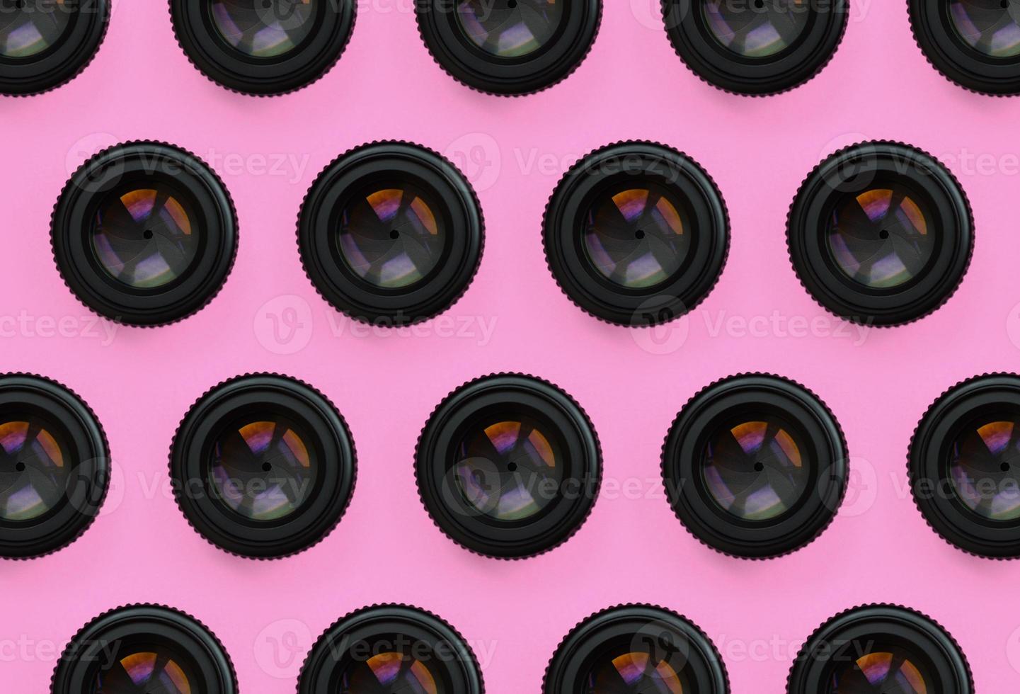 quelques objectifs d'appareil photo avec une ouverture fermée se trouvent sur un fond de texture de papier de couleur rose pastel de mode dans un concept minimal. motif tendance abstrait