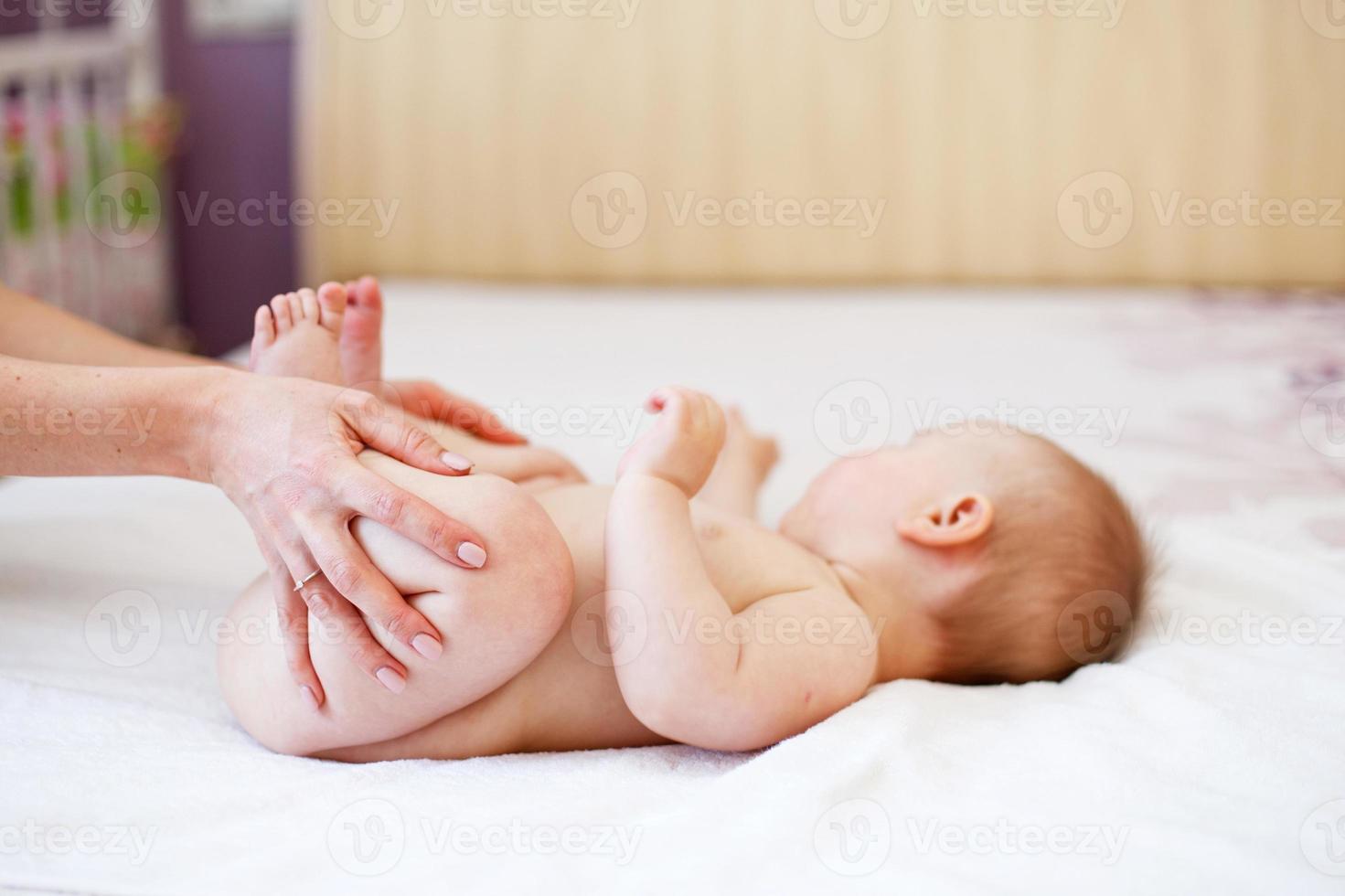 maman fait de la gymnastique pour un enfant. mère massant bébé au lit à la maison photo