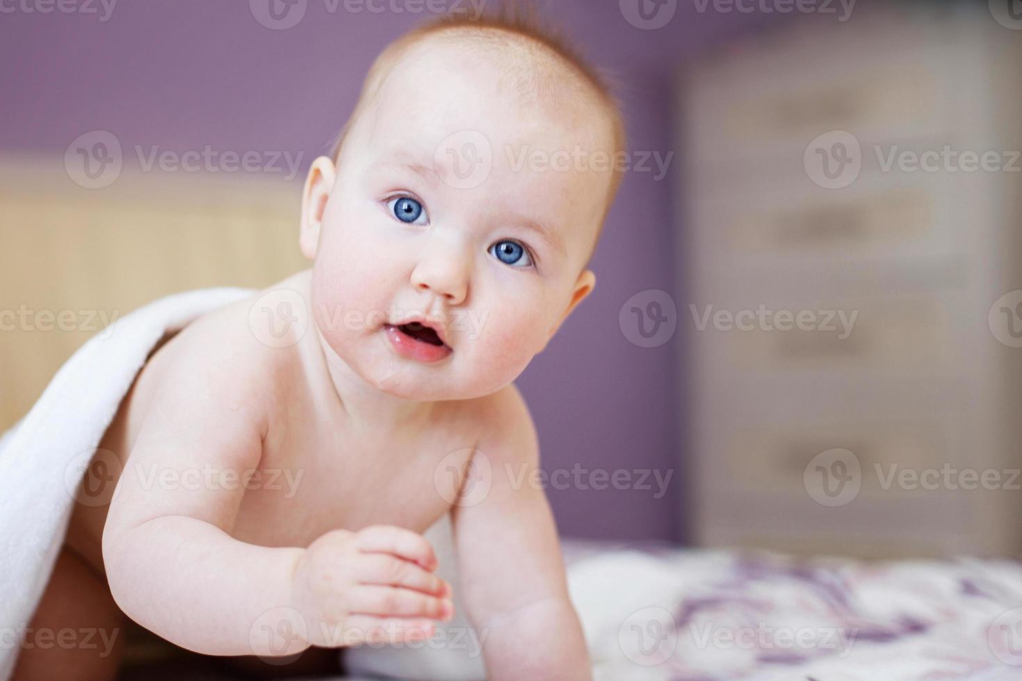 bébé mignon regardant la caméra sous une serviette blanche. portrait d'un enfant mignon photo