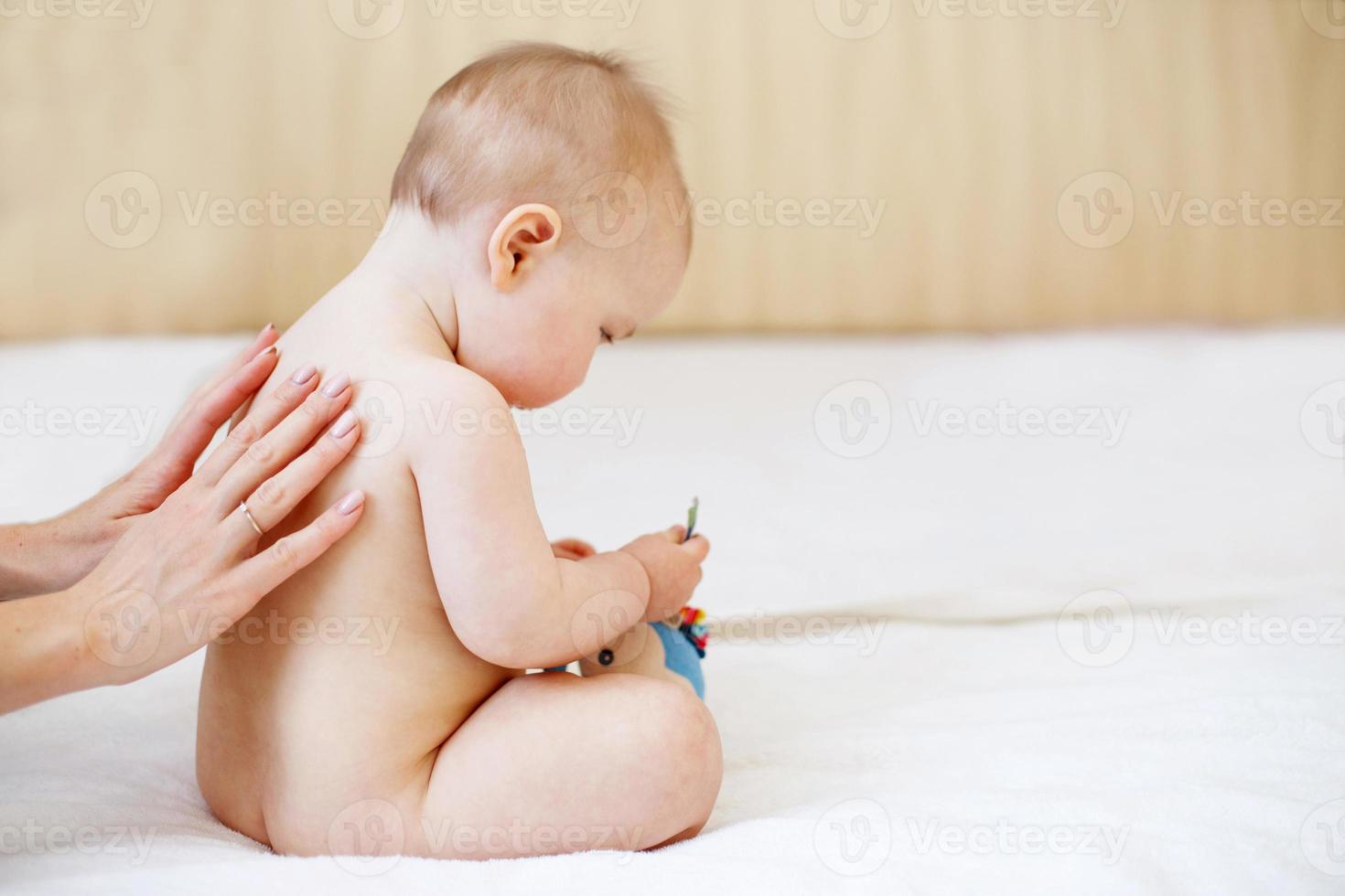 mère et bébé. famille heureuse. l'amour et la tendresse de maman. mère massant bébé dans le lit à la maison photo