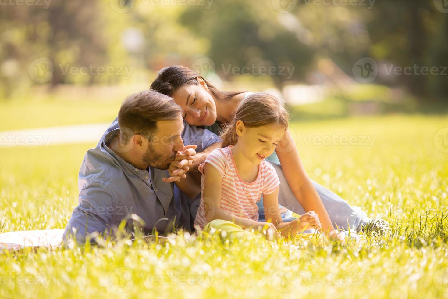 jeune famille heureuse avec une petite fille mignonne s'amusant dans le parc par une journée ensoleillée photo