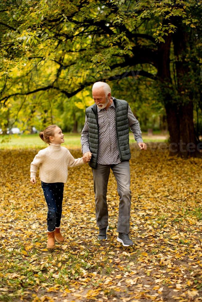 grand-père passe du temps avec sa petite-fille dans le parc le jour de l'automne photo