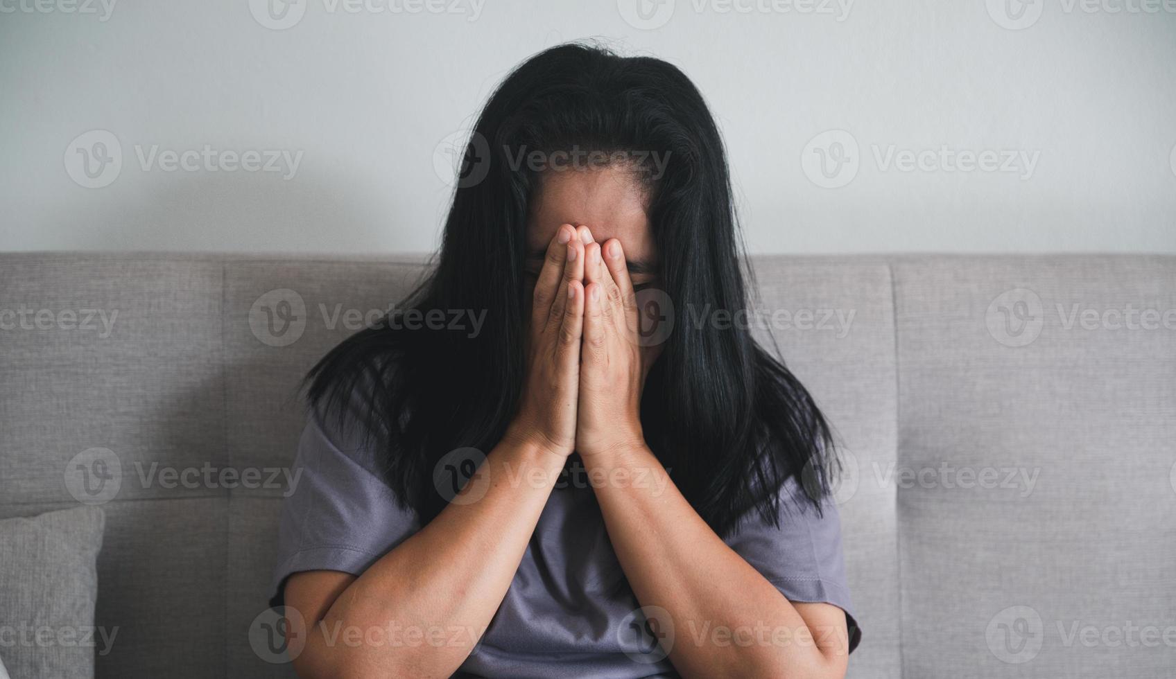 schizophrénie avec concept de dépression solitaire et triste en santé mentale. femme déprimée assise sur le canapé à la maison avec une pièce sombre se sentant misérable. les femmes sont déprimées, craintives et malheureuses. photo