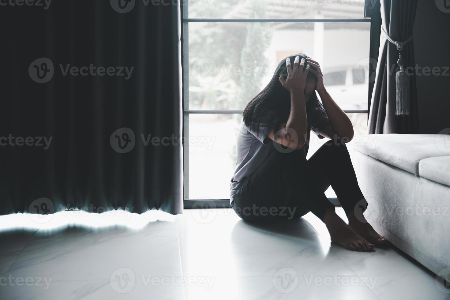 schizophrénie avec concept de dépression solitaire et triste en santé mentale. femme déprimée assise contre le sol à la maison avec une pièce sombre se sentant misérable. les femmes sont déprimées, craintives et malheureuses. photo