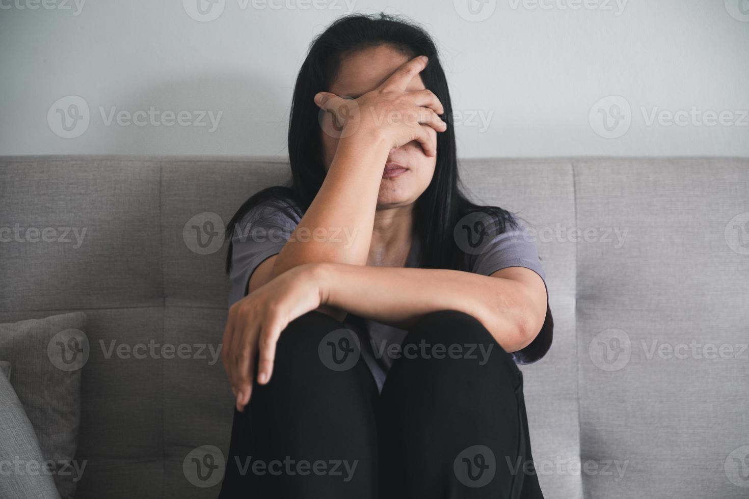 schizophrénie avec concept de dépression solitaire et triste en santé mentale. femme déprimée assise sur le canapé à la maison avec une pièce sombre se sentant misérable. les femmes sont déprimées, craintives et malheureuses. photo