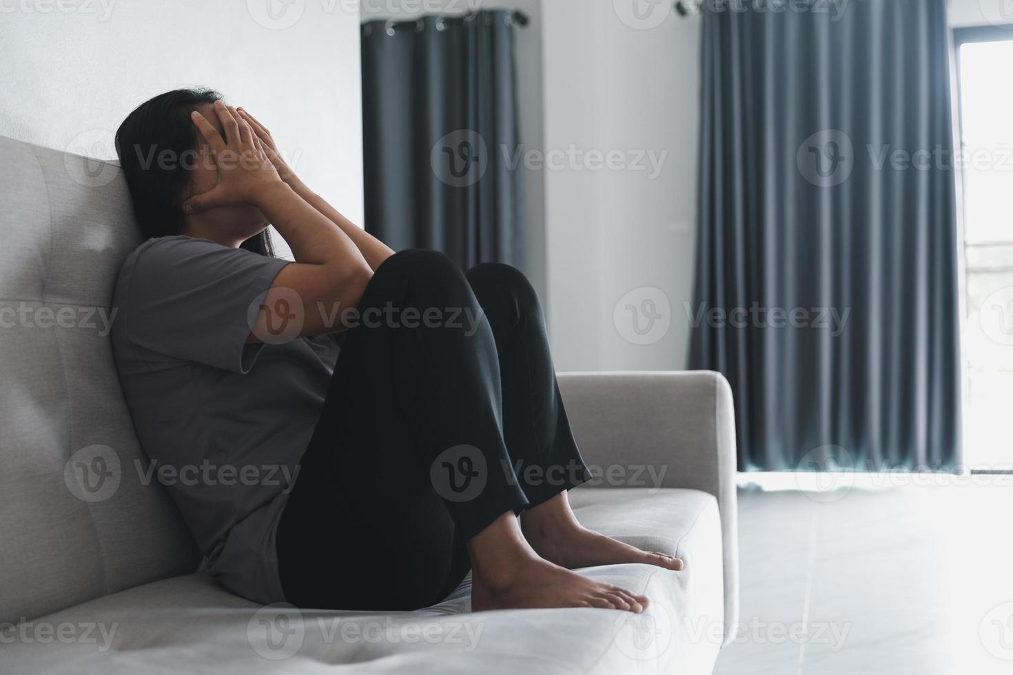 schizophrénie avec concept de dépression solitaire et triste en santé mentale. femme déprimée assise sur le canapé à la maison avec une pièce sombre se sentant misérable. les femmes sont déprimées, craintives et malheureuses. photo