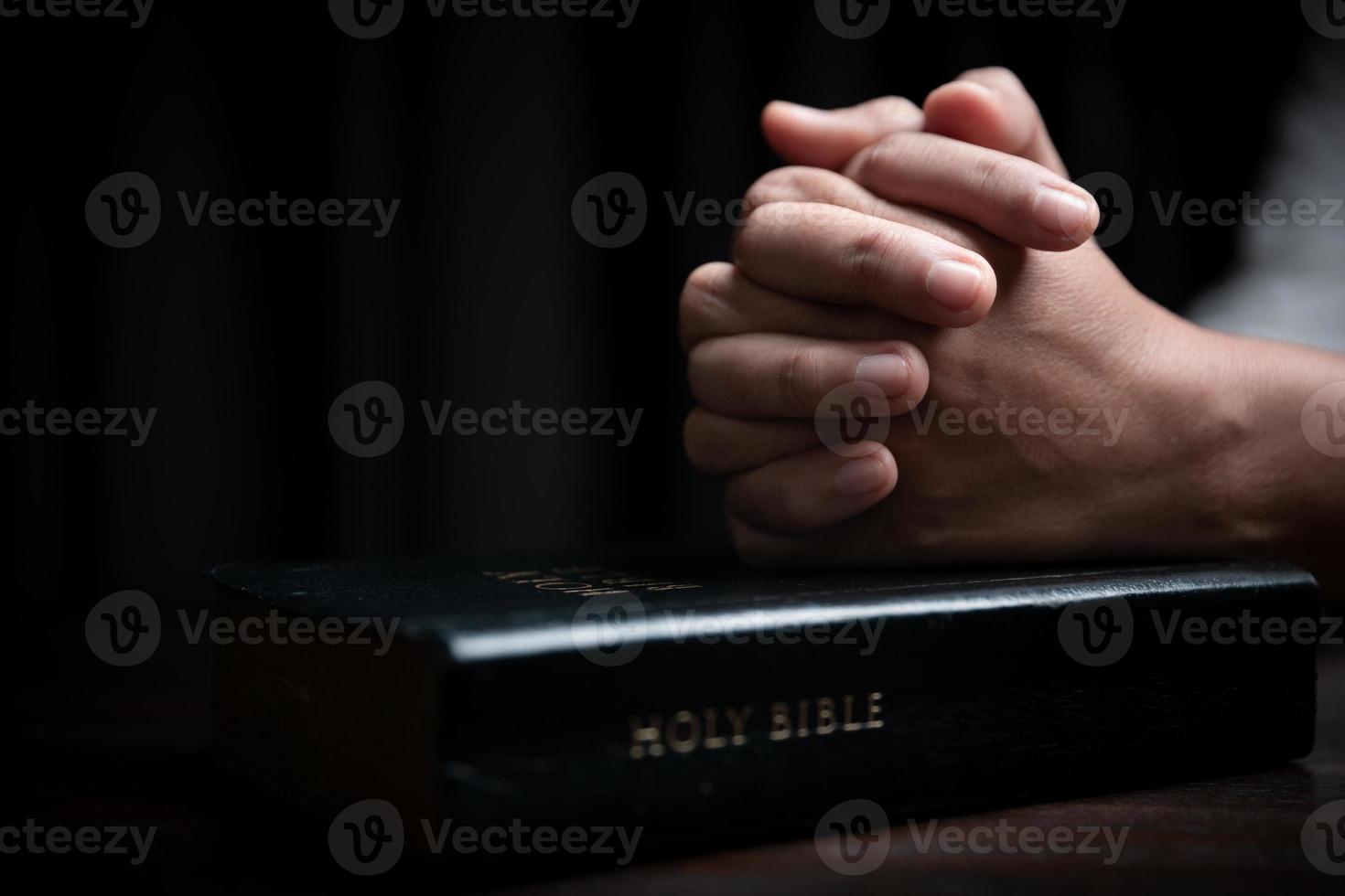 foi avec le concept de la sainte bible. mains d'un dieu de prière féminin avec la sainte bible sur fond noir à l'église. une femme chrétienne qui croit en jésus lit et étudie la grâce des saintes écritures. photo