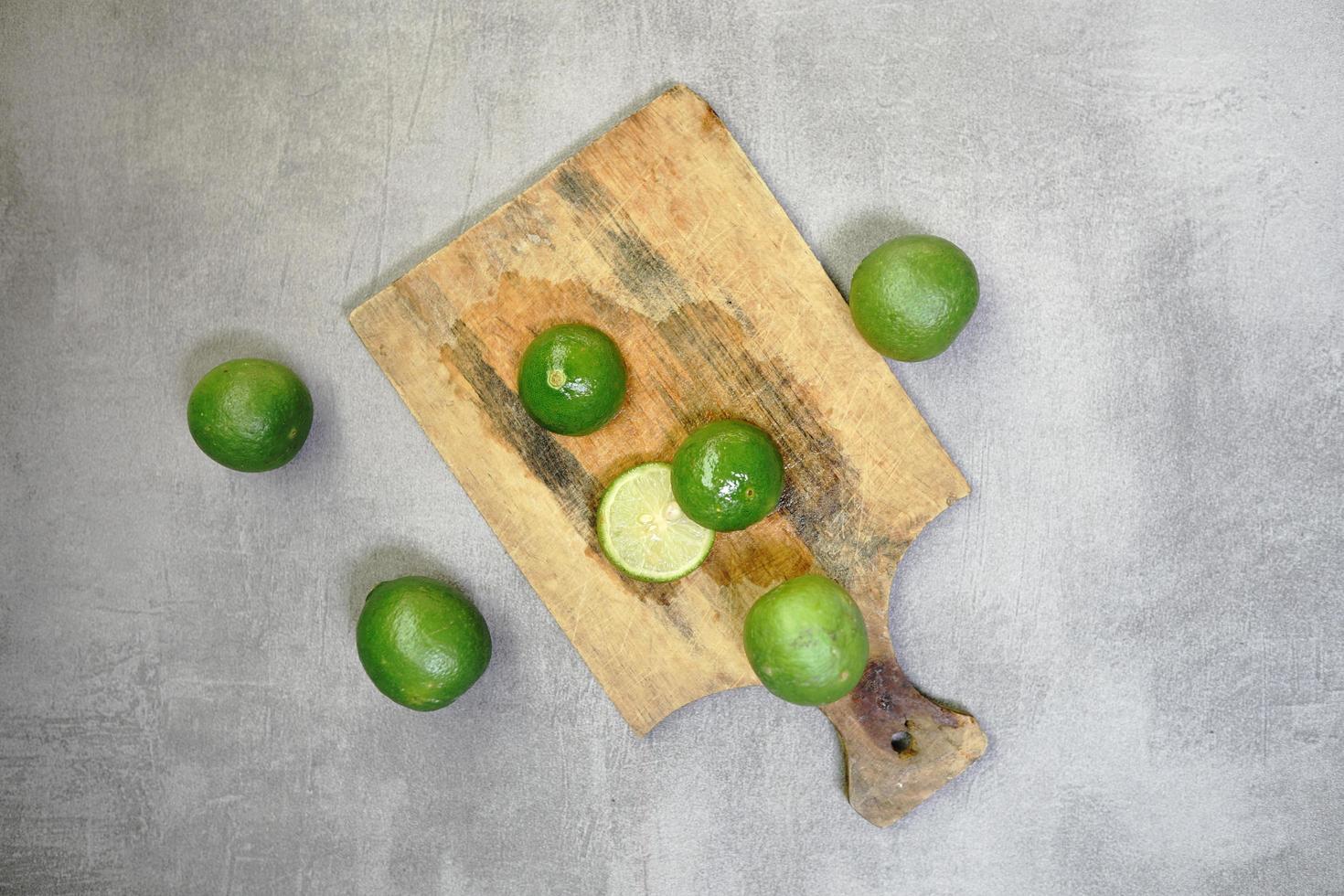 citron vert frais sur une planche à découper sur fond de béton photo