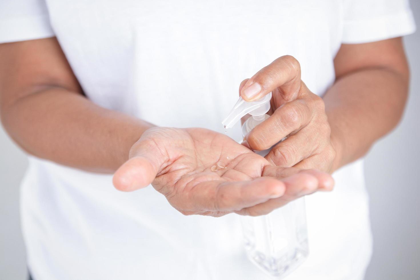 une femme âgée en vêtements blancs se lave les mains avec du gel d'alcool. prévenir l'infection par le coronavirus. concept de protection contre le virus covid-19 photo