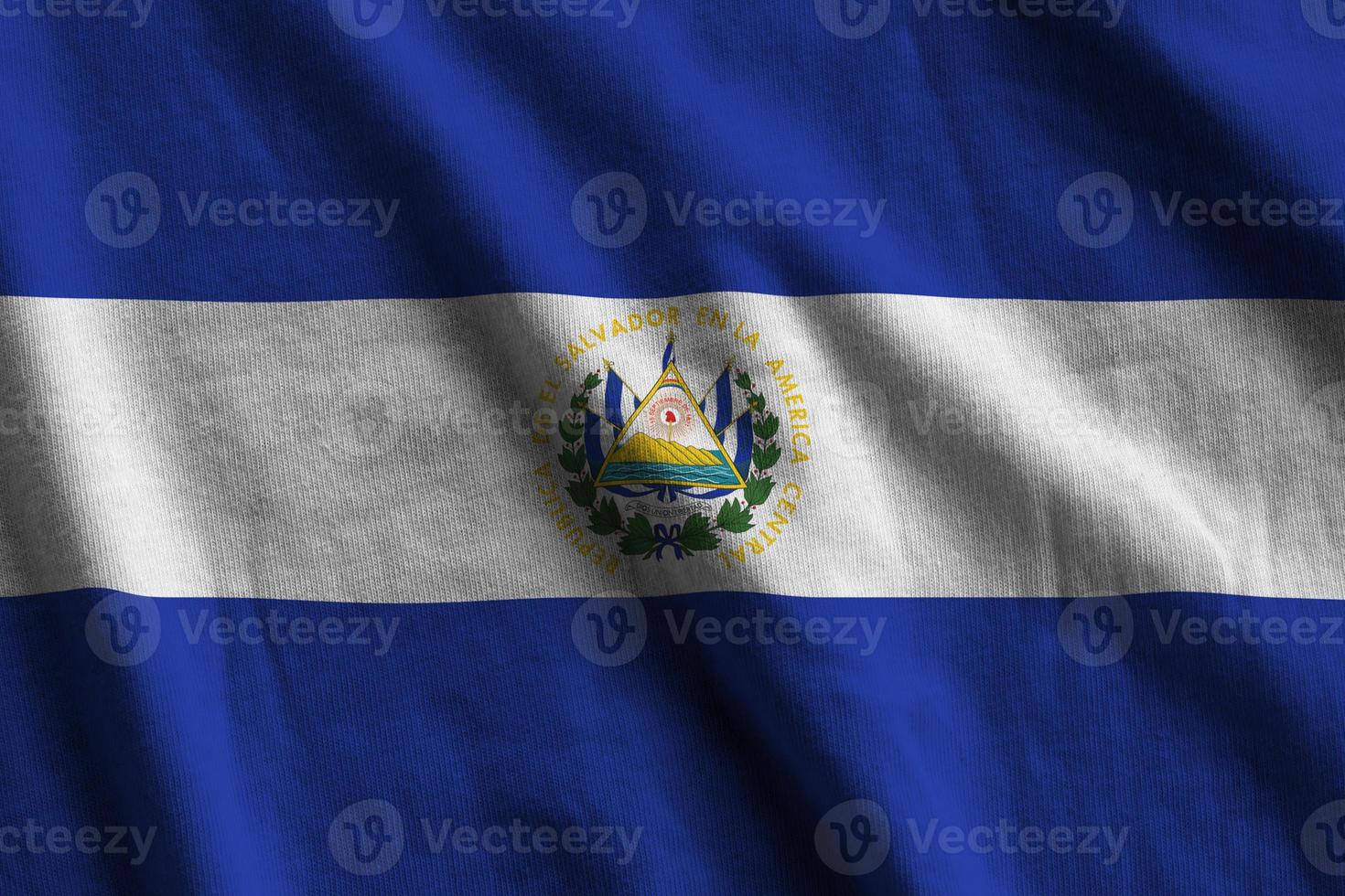 drapeau du salvador avec de grands plis agitant de près sous la lumière du studio à l'intérieur. les symboles et couleurs officiels de la bannière photo