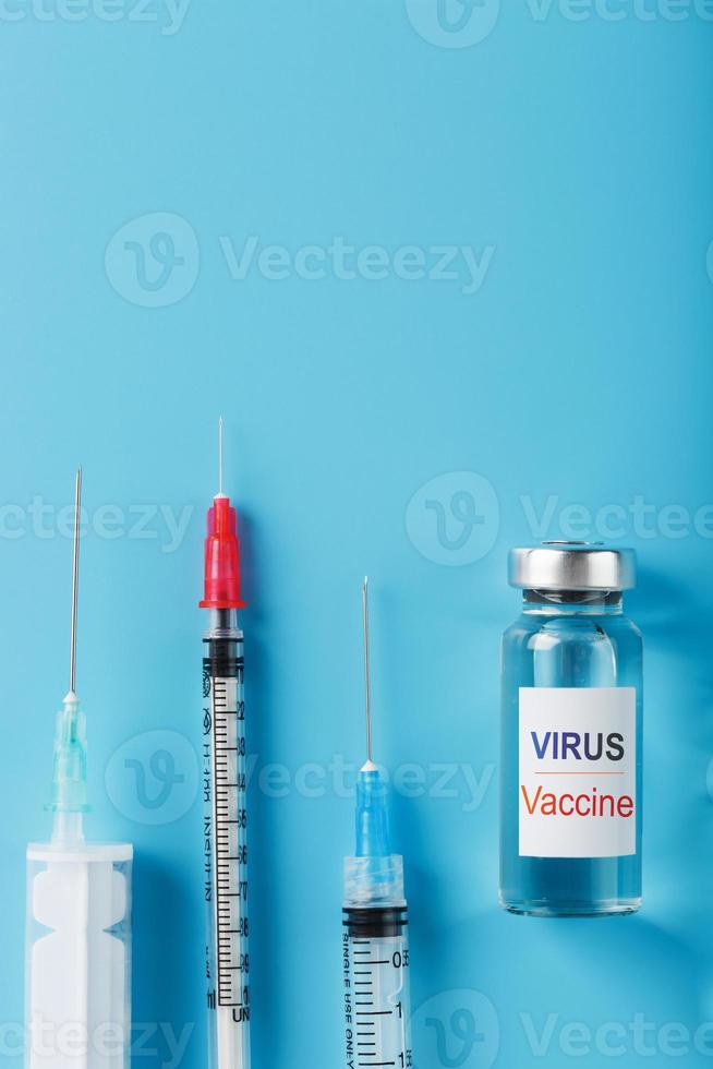 seringues et ampoule avec le vaccin contre le virus des maladies sur fond bleu. photo