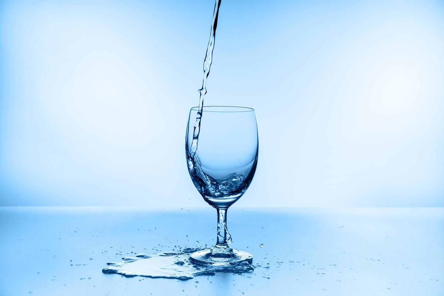 collection d'éclaboussures d'eau dans un verre à vin isolé sur fond bleu photo