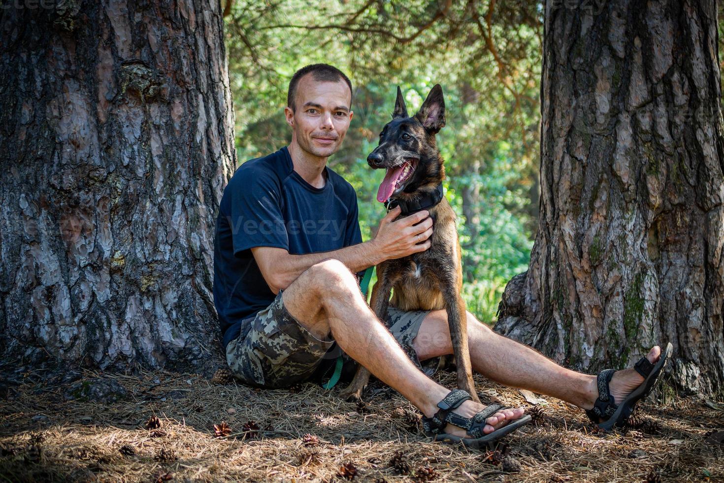 le jeune hipster caucasien passe du temps avec son chien dans le parc par une journée d'été ensoleillée. le concept d'un animal de compagnie en tant que membre de la famille photo