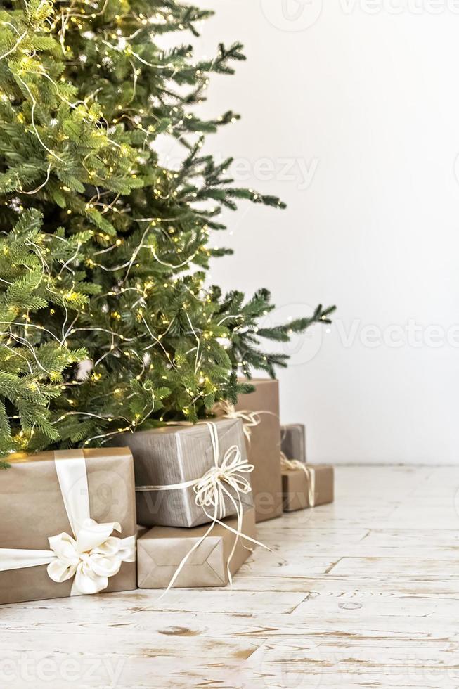 beaux coffrets cadeaux sur le sol près du sapin de noël dans la chambre. concept de noël et du nouvel an photo